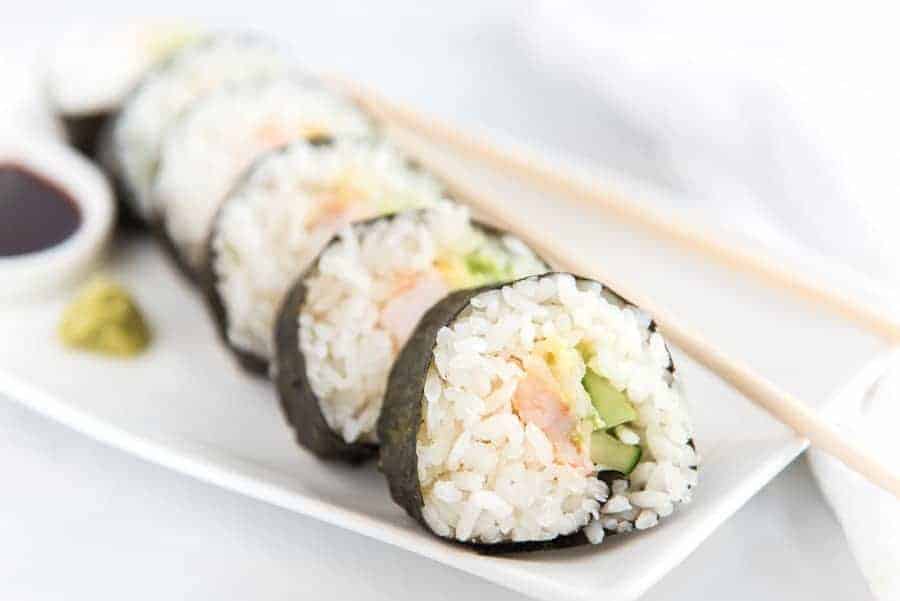 easy shrimp sushi roll on white dish with chopsticks.