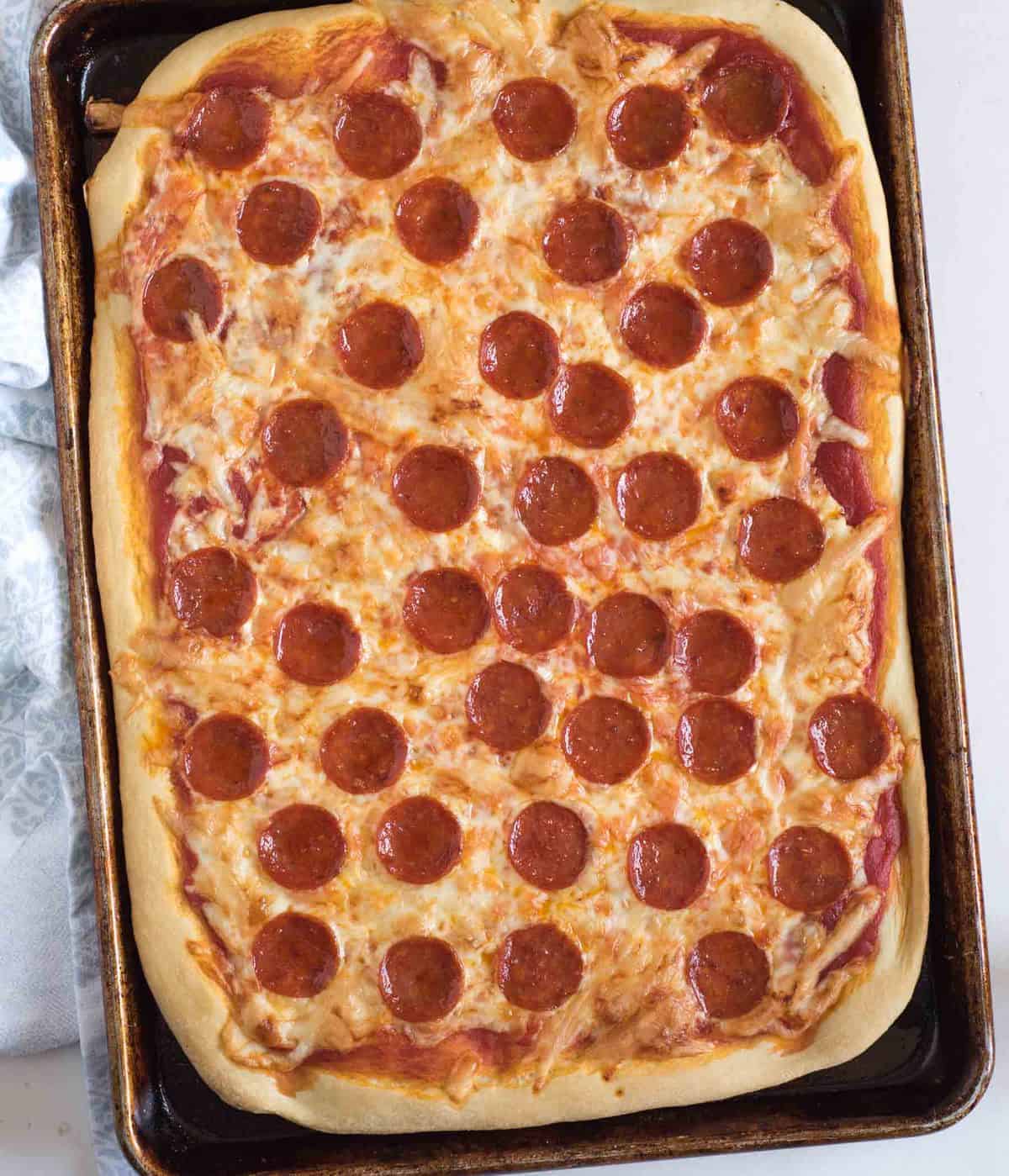 Top view of a cheese and pepperoni pizza on a sheet pan.