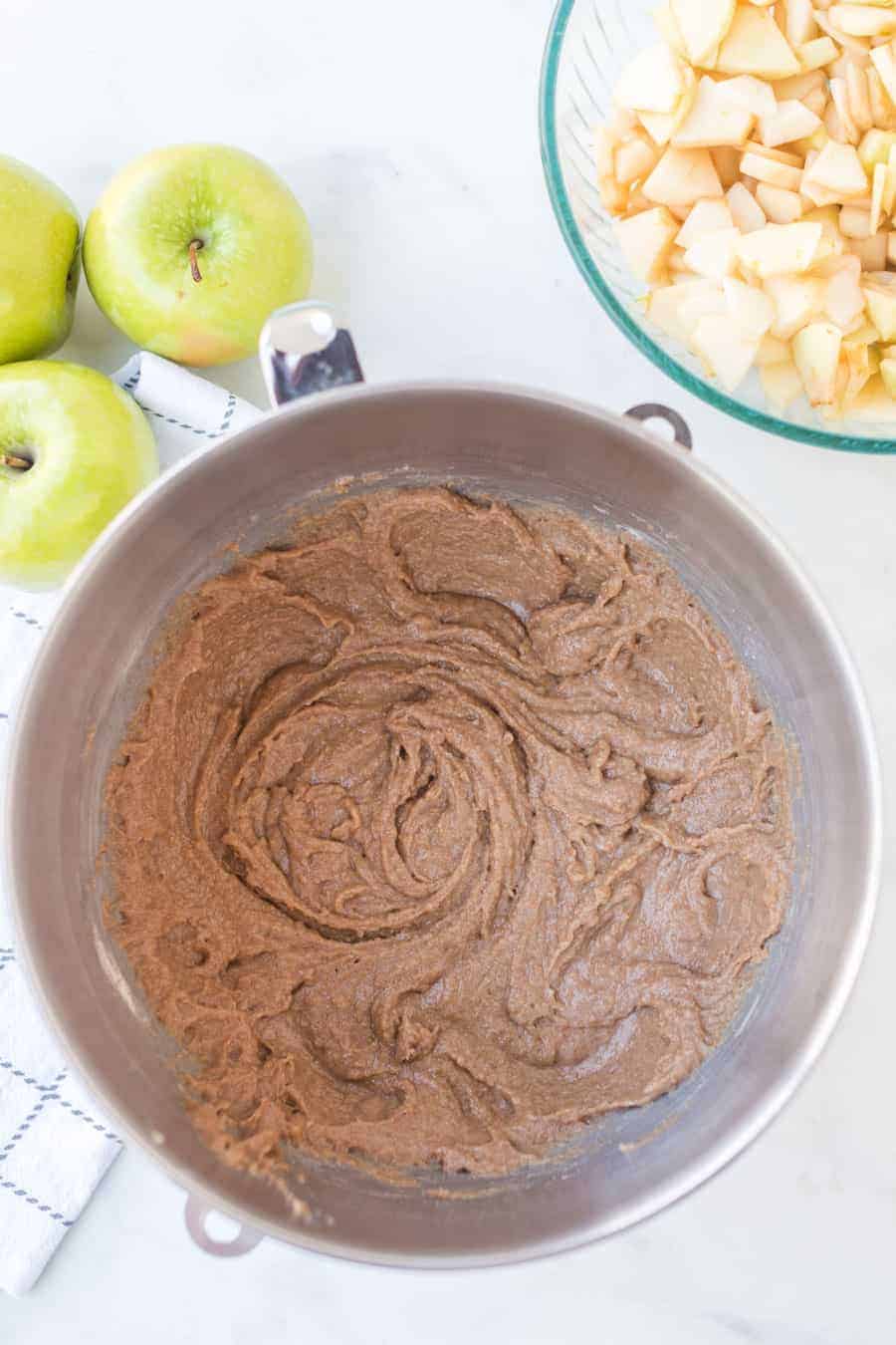 mixing bowl filled with brown sugar cinnamon mixture green apples in the background.