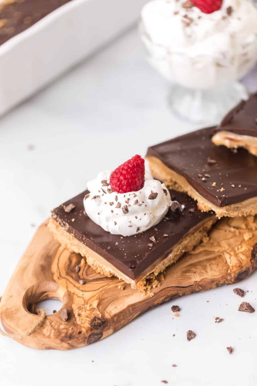 chocolate caramel tart with whipped cream and a raspberry on top.