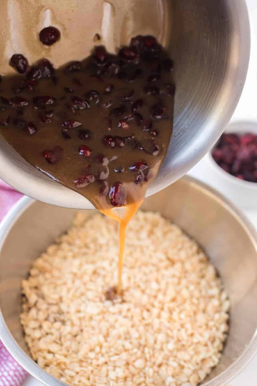 sticky sauce and cranberries being poured into granola.