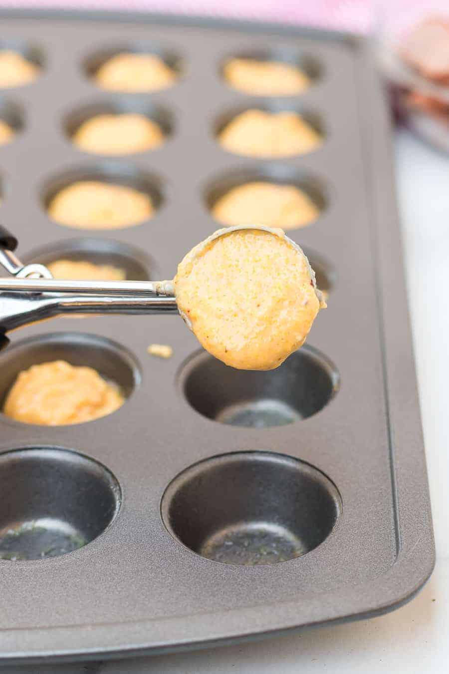 a small scoop measuring corndog dough into a mini muffin tin.