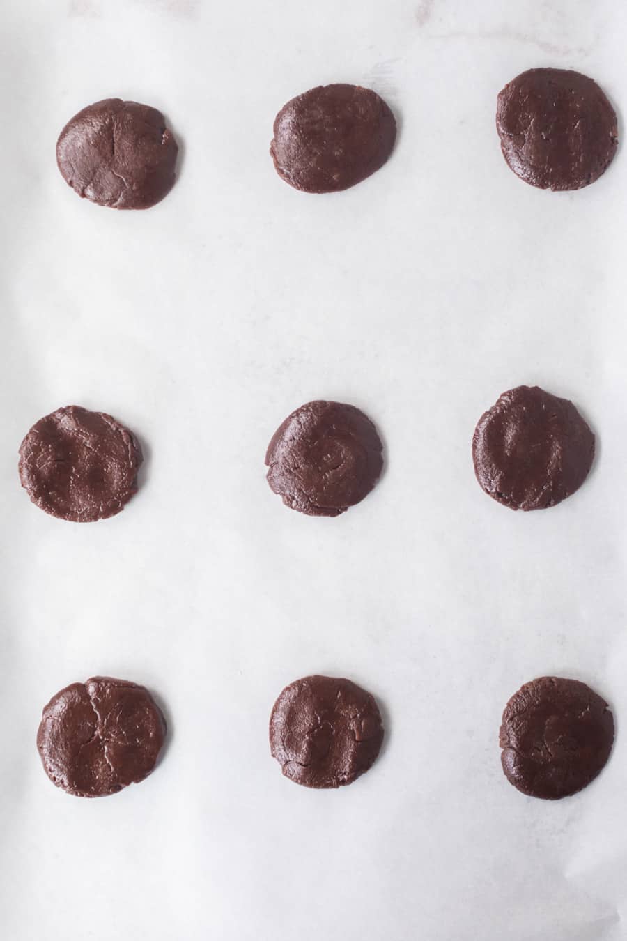 the top of homemade oreos on parchment on a baking sheet, raw