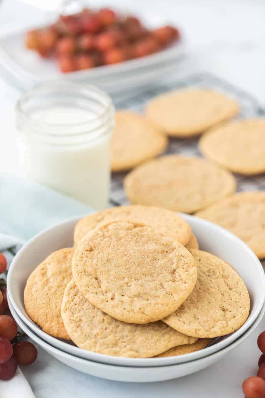 a bowl and a cooling rack of thin golden cookies.