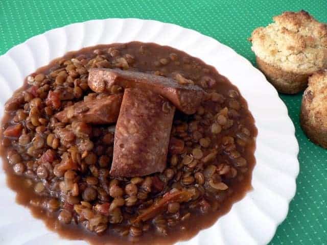 spicy lentils with sausage on a white plate.