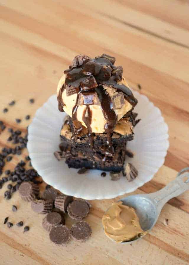 a tower of brownies, ice cream, and fudge sauce on a white plate