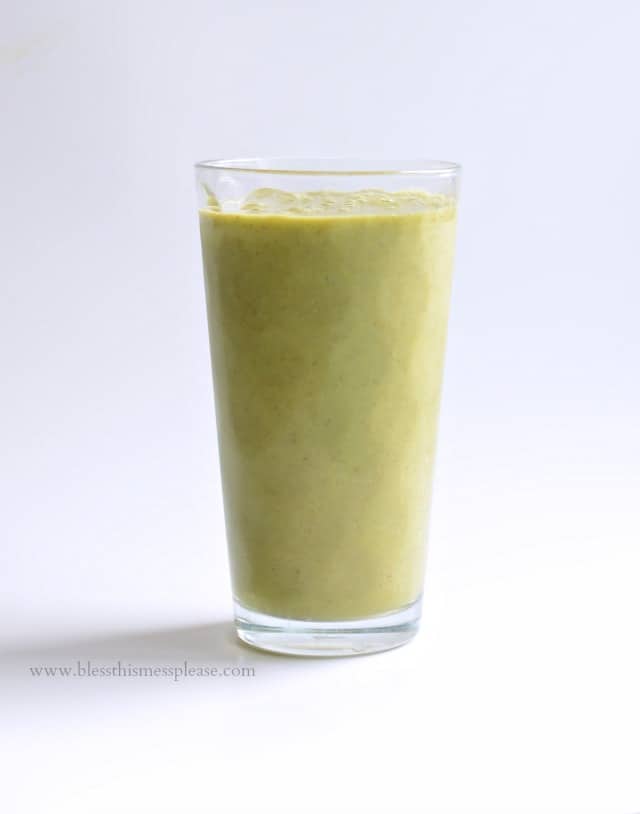 A workout recovery smoothie in a clear pint glass on a white counter.