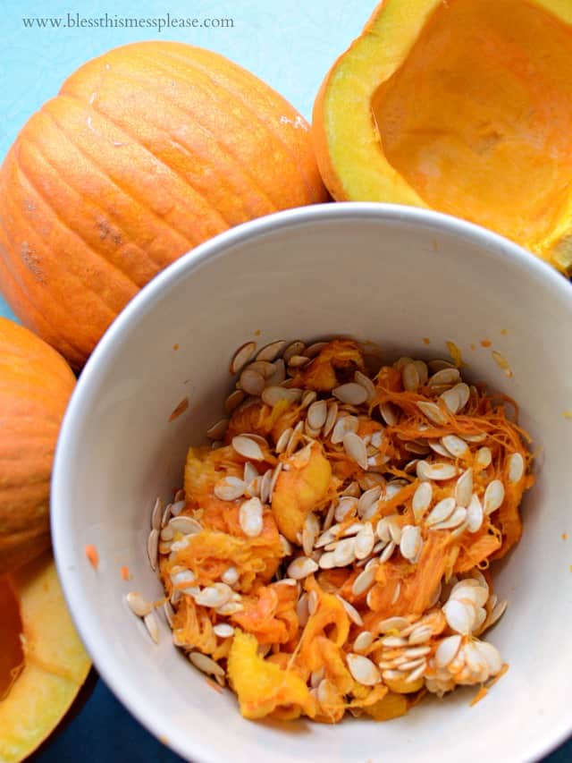 A pumpkin cut in half with the innards in a bowl.