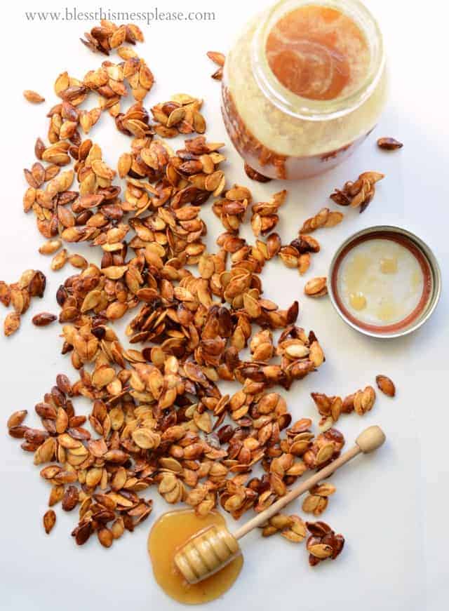 Top view of Honey Roasted Pumpkin Seeds with Cinnamon with a honey stir stick next to it.