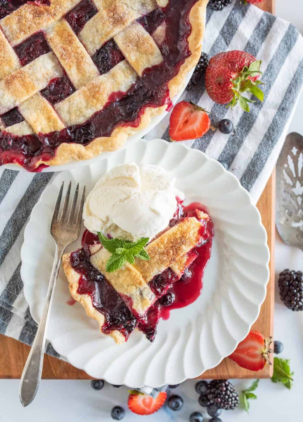 top view of a plate of tripe berry pie with ice cream next to the pie.