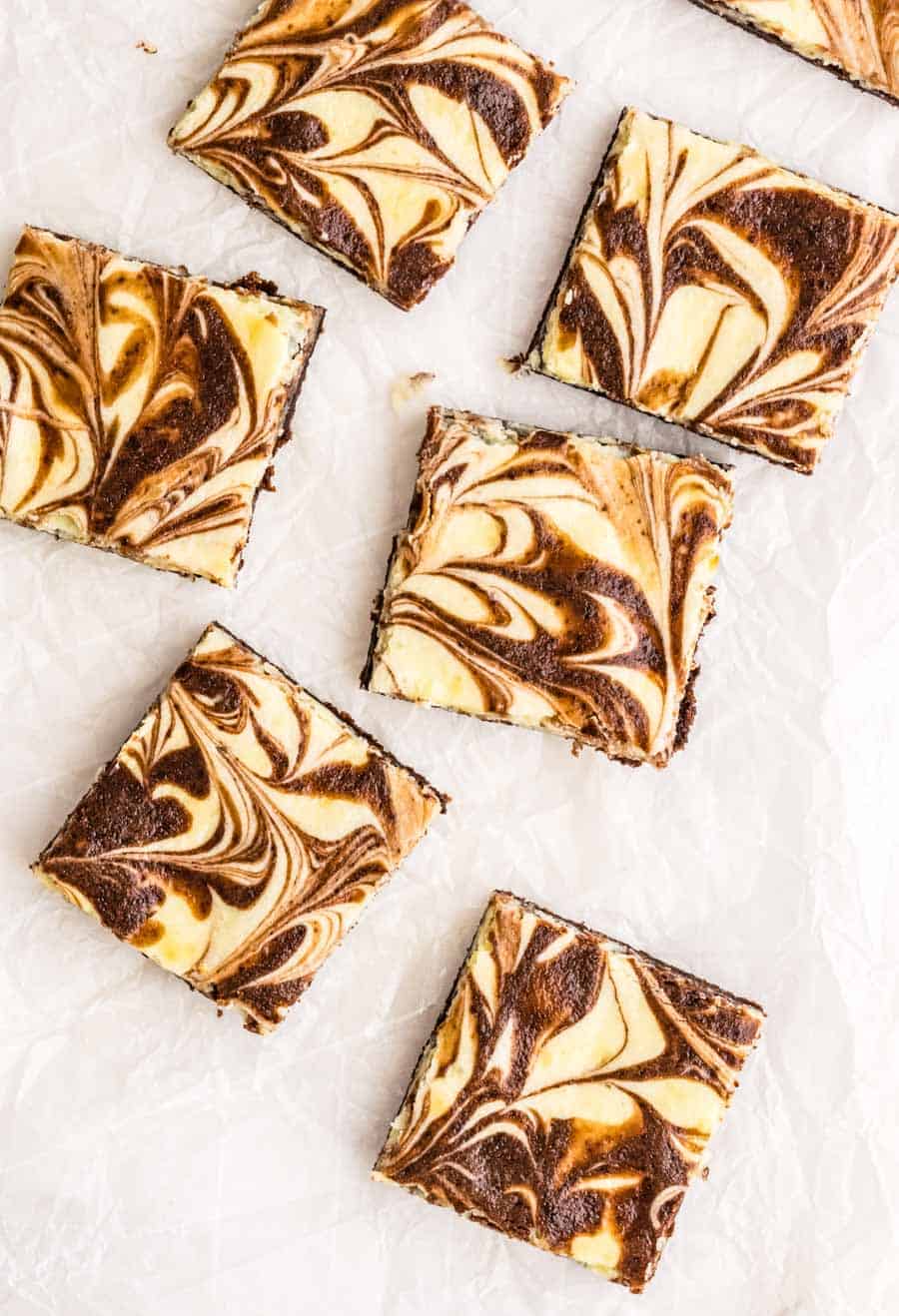 Top view of six cheesecake brownie squares on parchment paper.