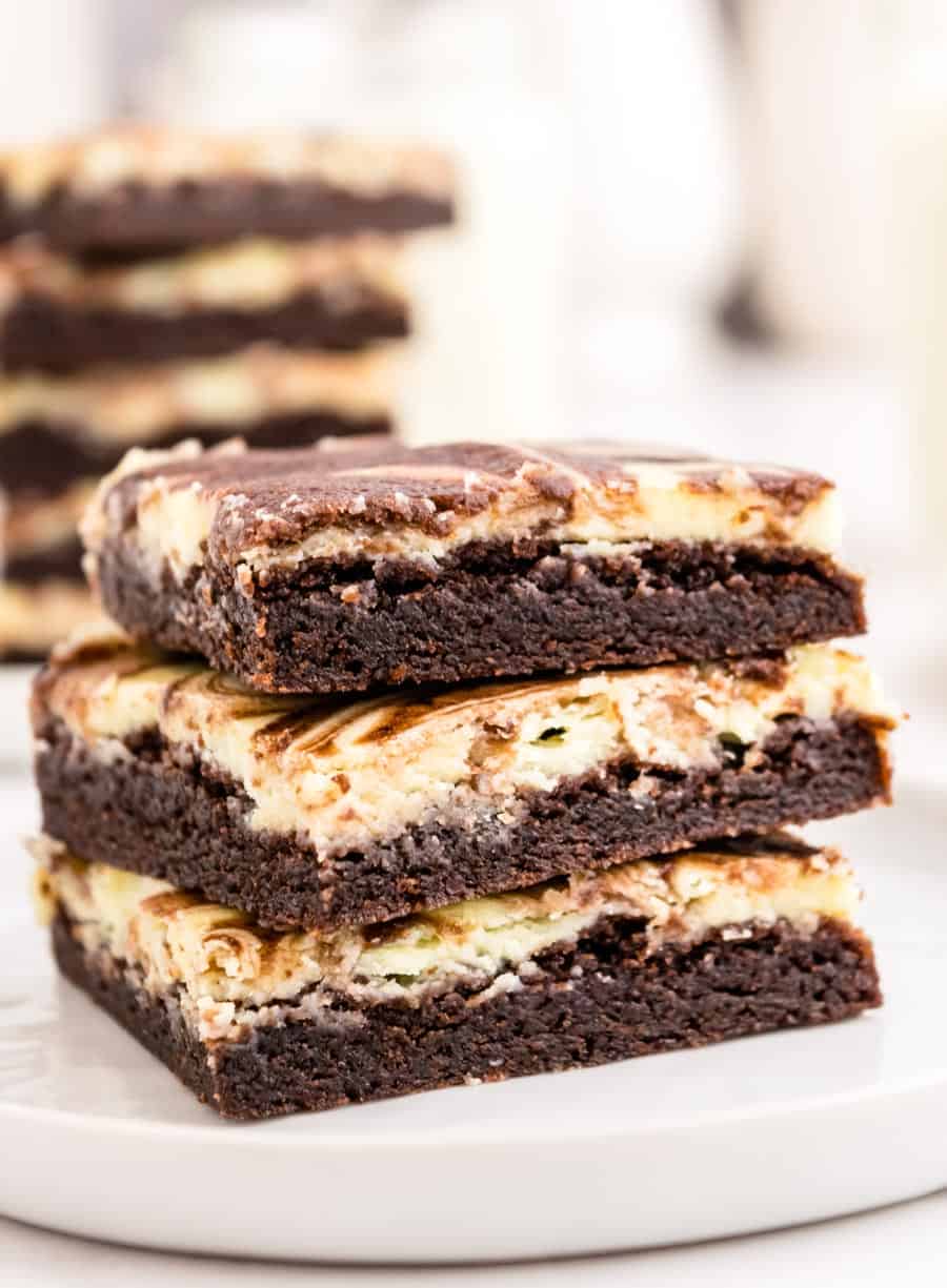 Close up of three cheesecake brownies stacked on a plate.