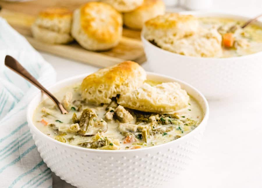 A close up picture of a bowl of slow cooker chicken pot pie topped with a biscuit.