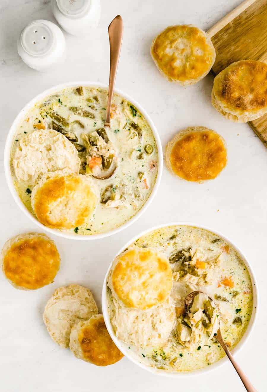 Top view of two bowls of slow cooker chicken pot pie with biscuits around the bowls.