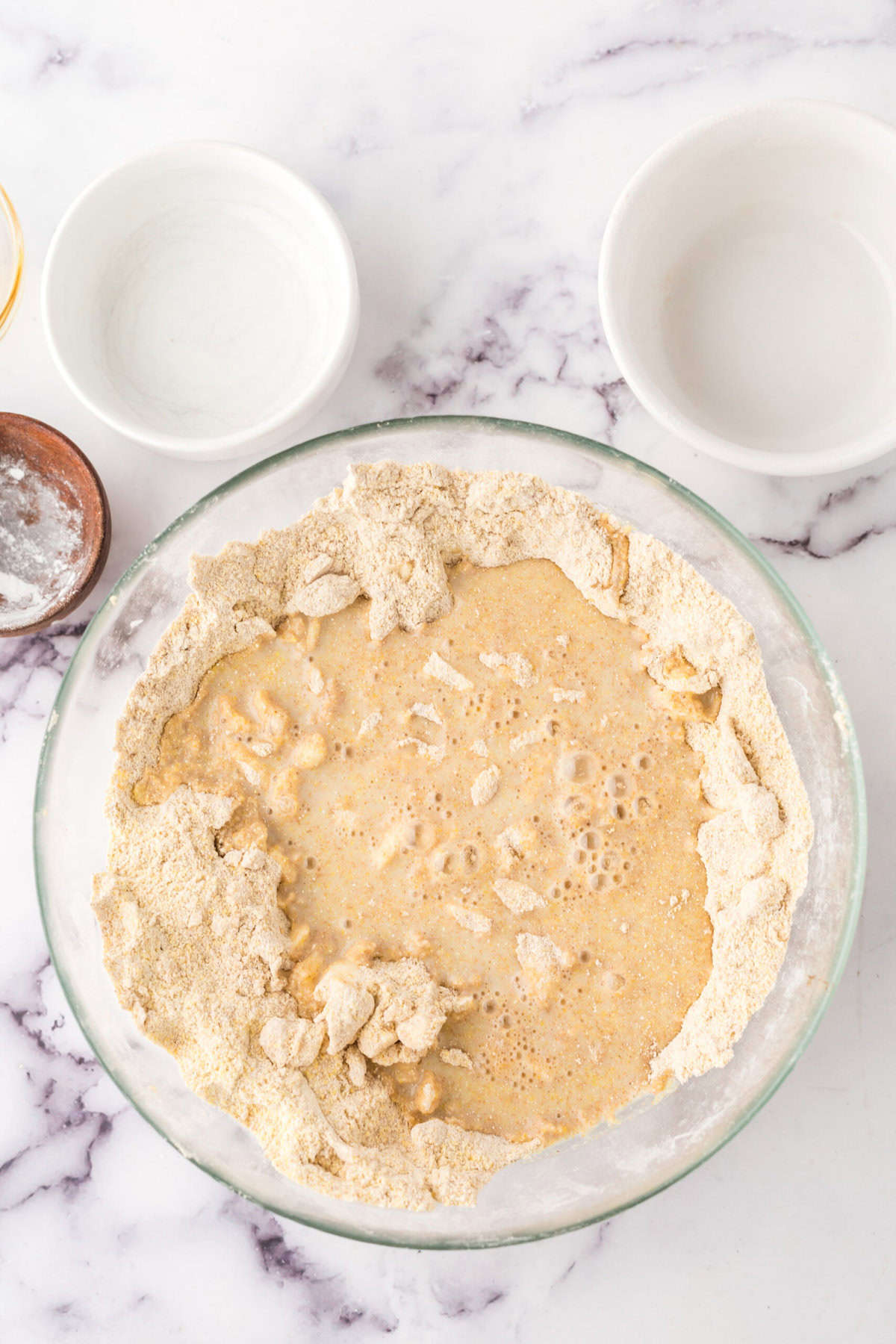Dough being mixed in a glass bowl for cornmeal biscuits.