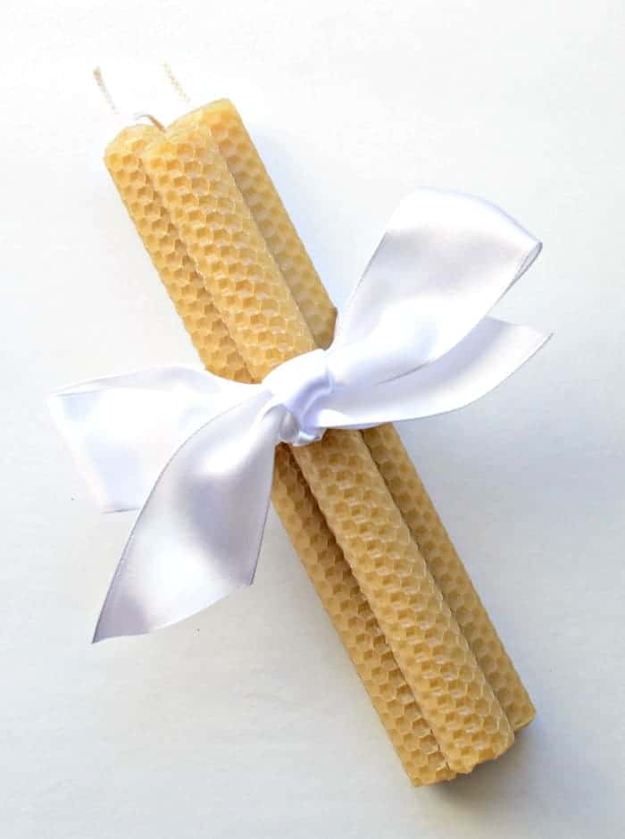 Three Simple DIY Beeswax Candles tied with a white ribbon on a white countertop.