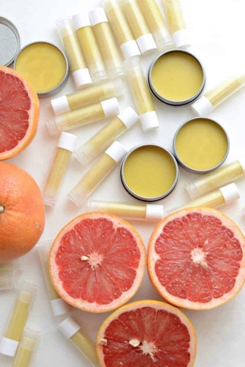 Top view of homemade beeswax lip balm in lip balm tubs and small pots surrounded by grapefruits.