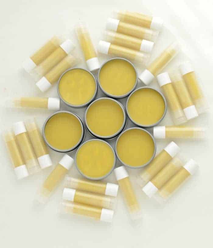 Eight pots and 40 tubes of homemade beeswax lip balm on a white counter.