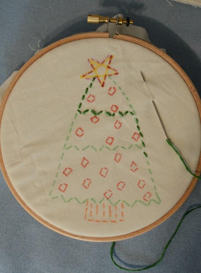 A simple embroidered ornament with the design drawn on the fabric and the ornament partially embroidered.