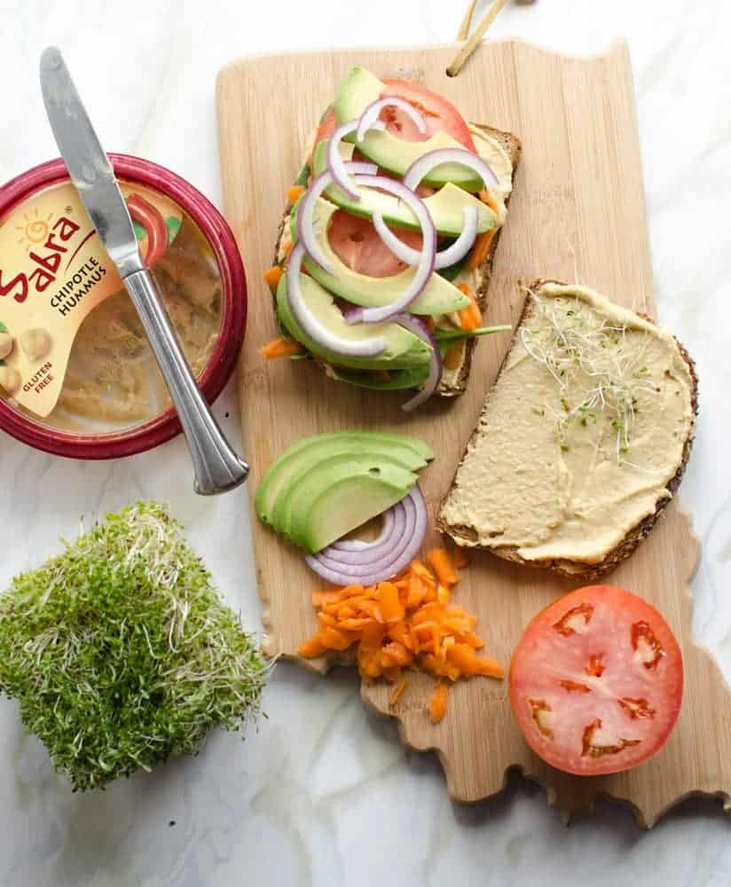 Ingredients for The Ultimate Hummus and Veggie Sandwich on a wooden cutting board the shape of the state of Indiana.