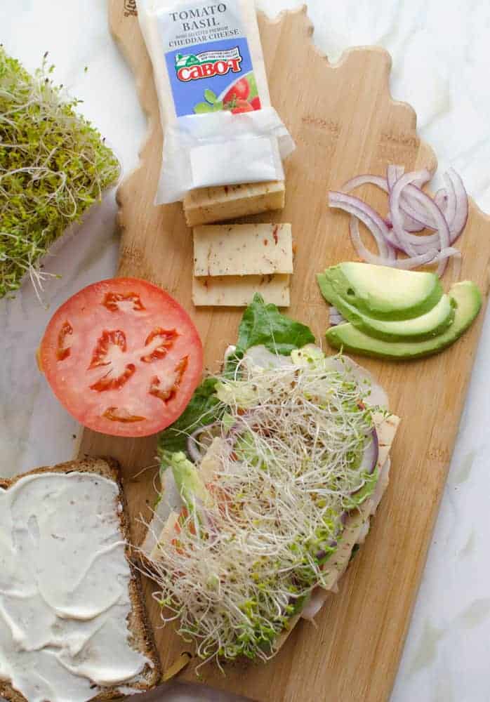 Ingredients for The Ultimate Hummus and Veggie Sandwich on a wooden cutting board the shape of the state of Indiana.