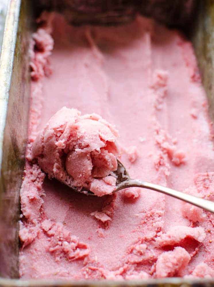 4 Ingredient Strawberry Frozen Yogurt in a loaf pan with a spoon scooping some out.