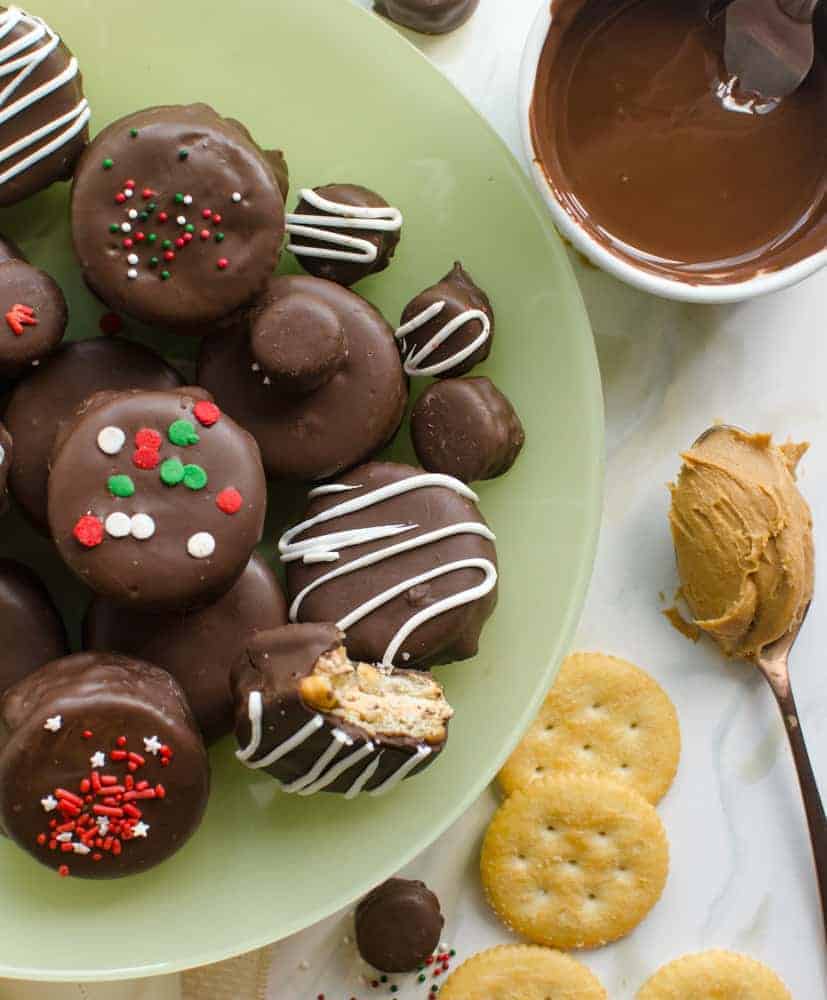 No-Bake Chocolate-Covered Fluffernutter Cookies on a light green plate with a white ramekin of melted chocolate and a spoonful of peanut butter next to them.