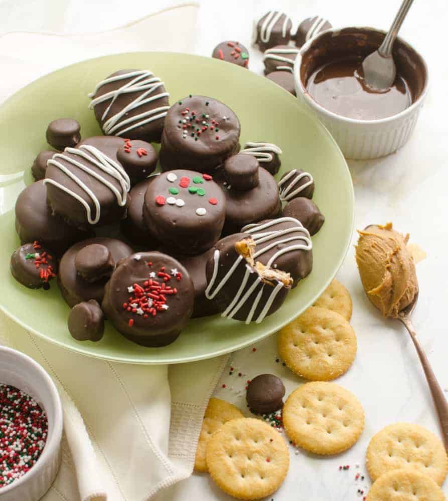 No-Bake Chocolate-Covered Fluffernutter Cookies on a light green plate with a white ramekin of melted chocolate and a spoonful of peanut butter next to them.