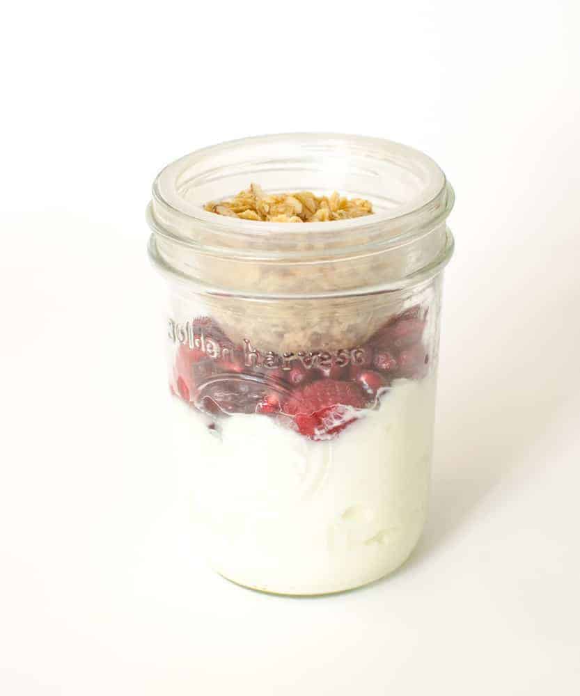 Greek yogurt, granola, and berries in a Mason jar.