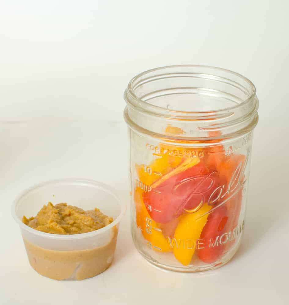 Bell peppers, carrots, and hummus in a Mason jar.