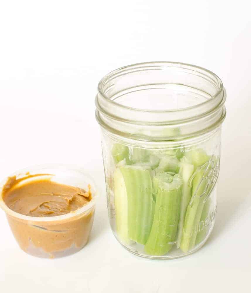 Celery sticks and peanut butter in a Mason jar.