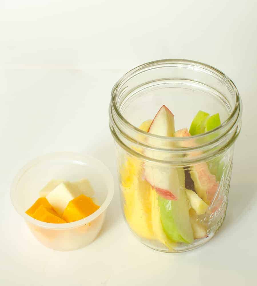 Apple slices and cheese cubes in a Mason jar.