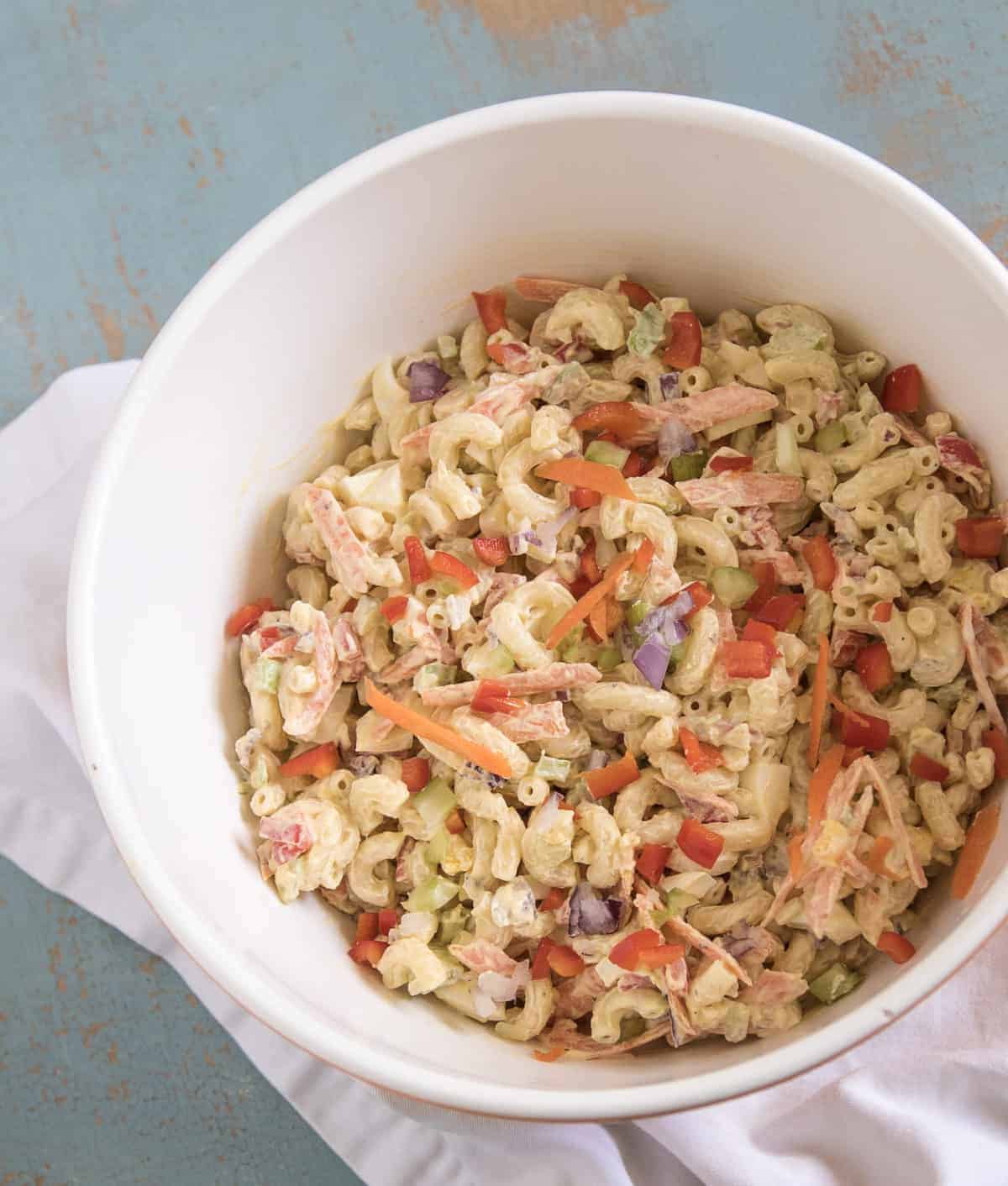 Classic Macaroni Salad in a white bowl resting on a white napkin.