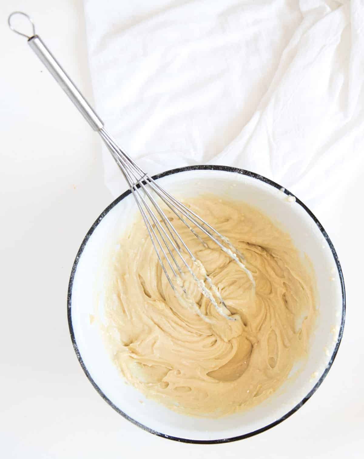 A white bowl with strawberry shortcake mixture and a wire whisk.