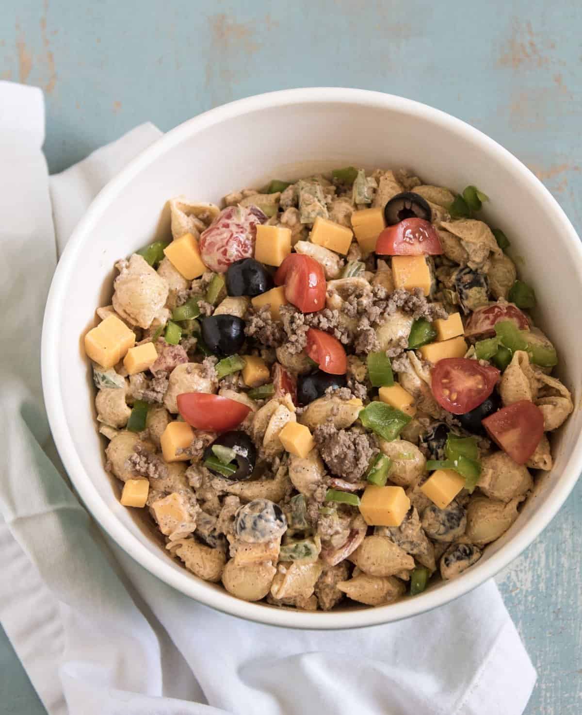 Creamy taco pasta salad in a white bowl resting on a white napkin.