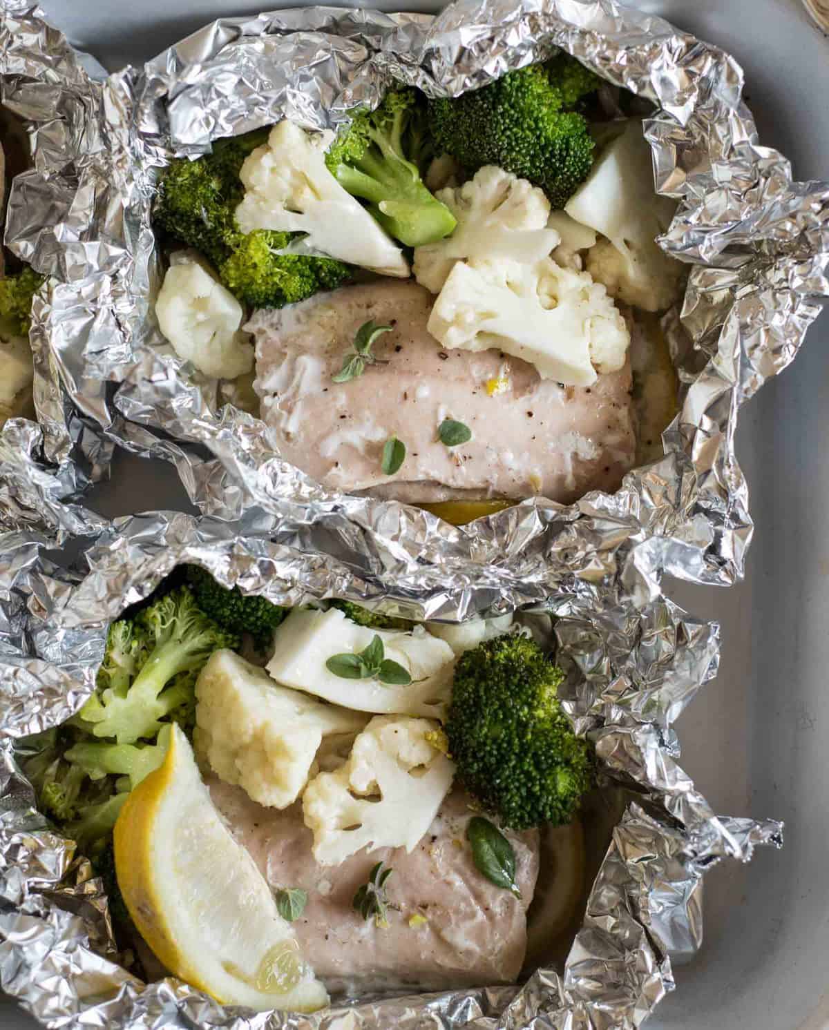 Top view of salmon, cauliflower, and broccoli in foil.