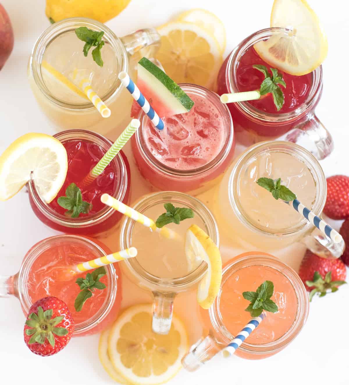 Top view of glass cups with a different flavor in each with straws and a mint leaf in each cup.