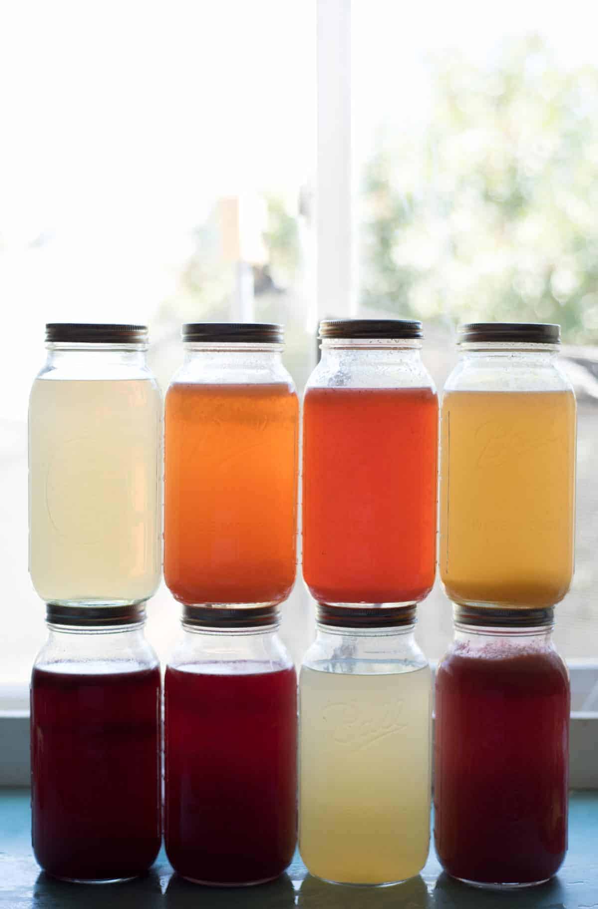 8 mason jars stacked 4x2 with different flavors and colors of lemonade in each.