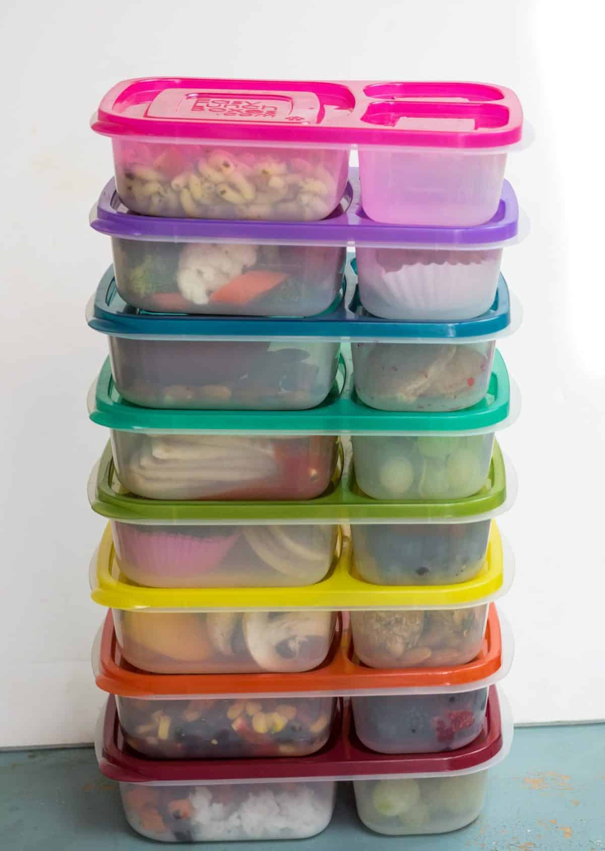 Lunch boxes stacked with different colored lids in a rainbow.
