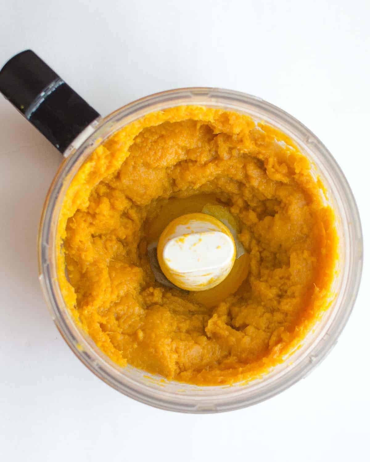 Pumpkin puree in a food processor bowl on a white counter.