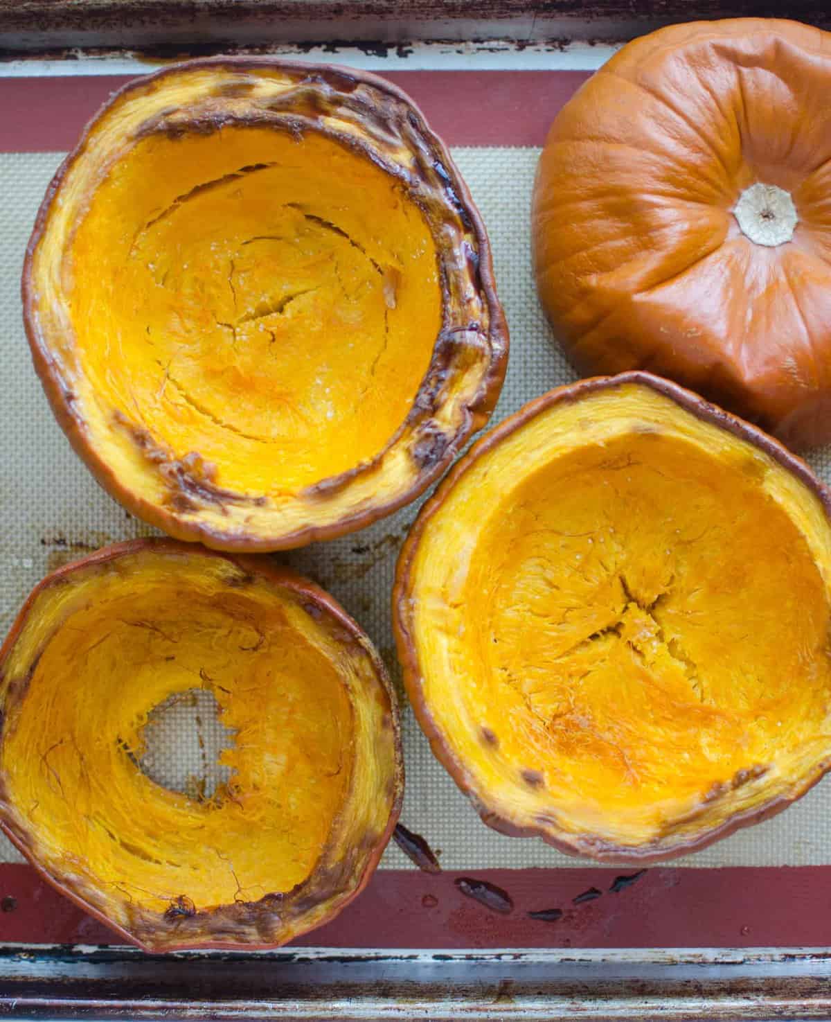 Cooked pumpkin on a rimmed baking sheet lined with a silicone baking mat.