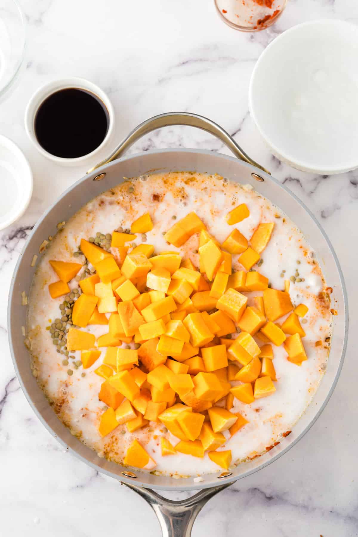 Adding squash and other ingredients to pan.
