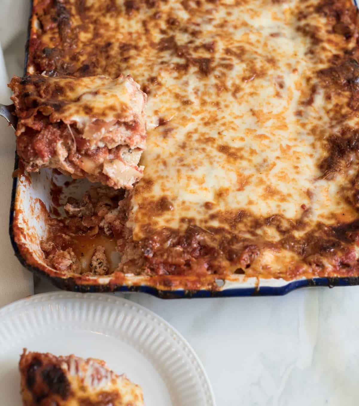 A piece of lasagna being removed by a thin metal spatula.