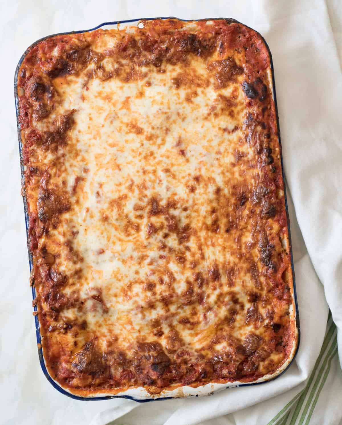 Top view of the Best Make-Ahead Lasagna after baking in a white enamel pan with blue rim.