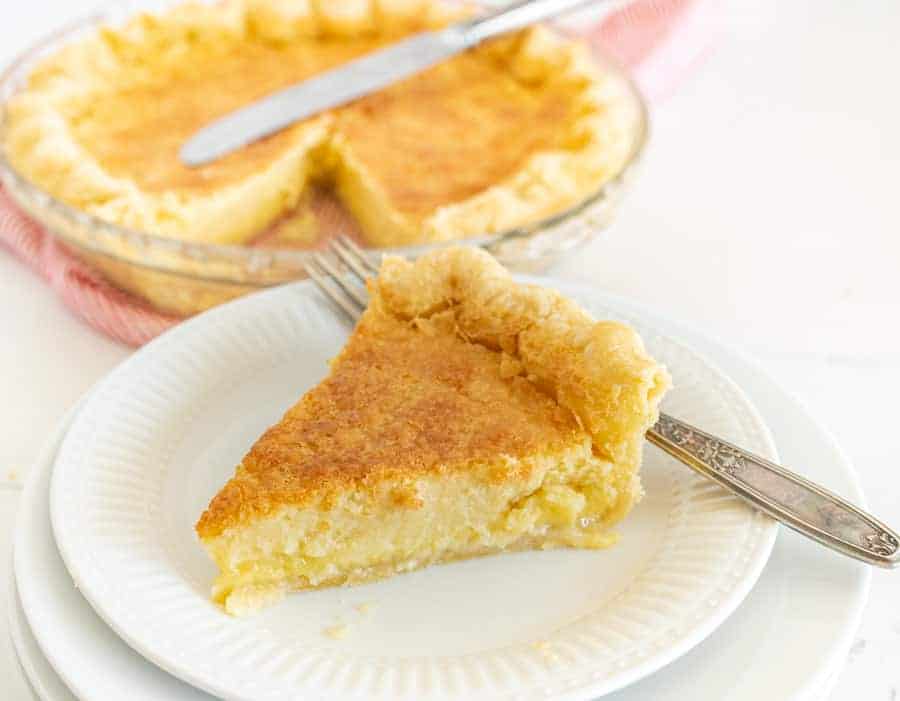 slice of buttermilk pie on a white plate with a fork.