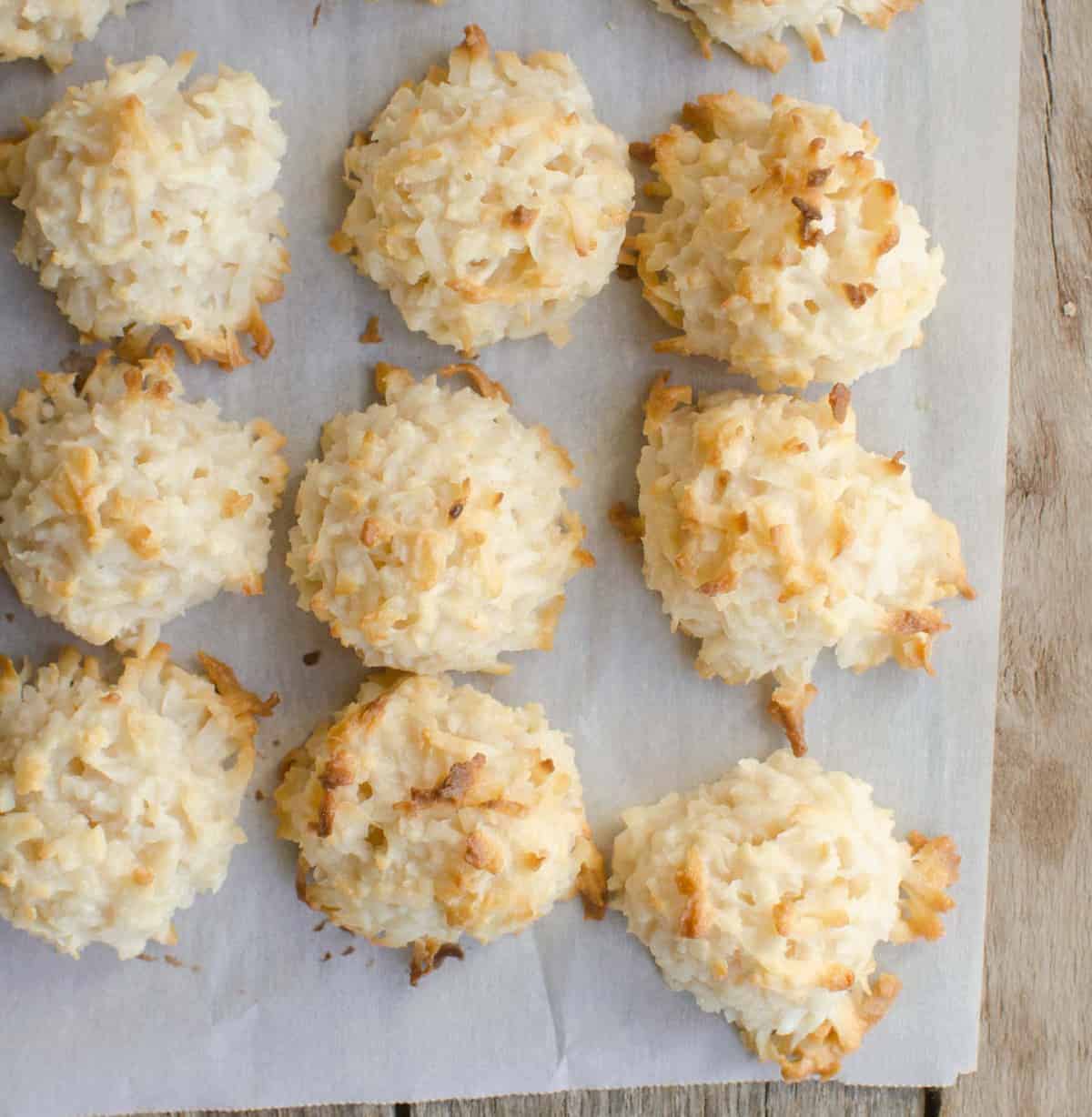 Top view of baked coconut macaroons on white parchment paper.