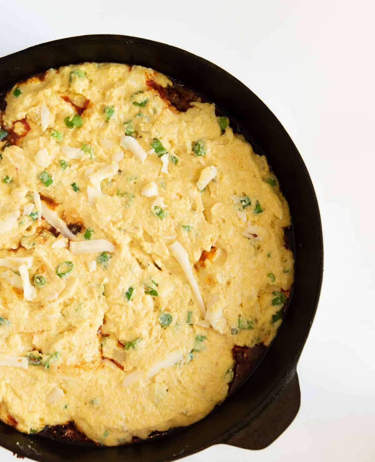 One Pan Tamale pie is made with a rich meat and vegetable filling topped with a golden cornbread crust that has cheese and green onions in it, all made in one skillet.