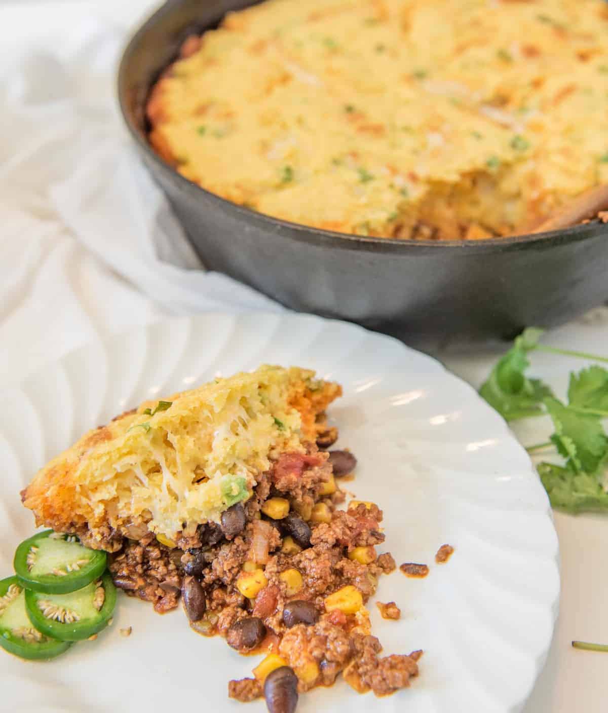 One Pan Tamale pie is made with a rich meat and vegetable filling topped with a golden cornbread crust that has cheese and green onions in it, all made in one skillet.