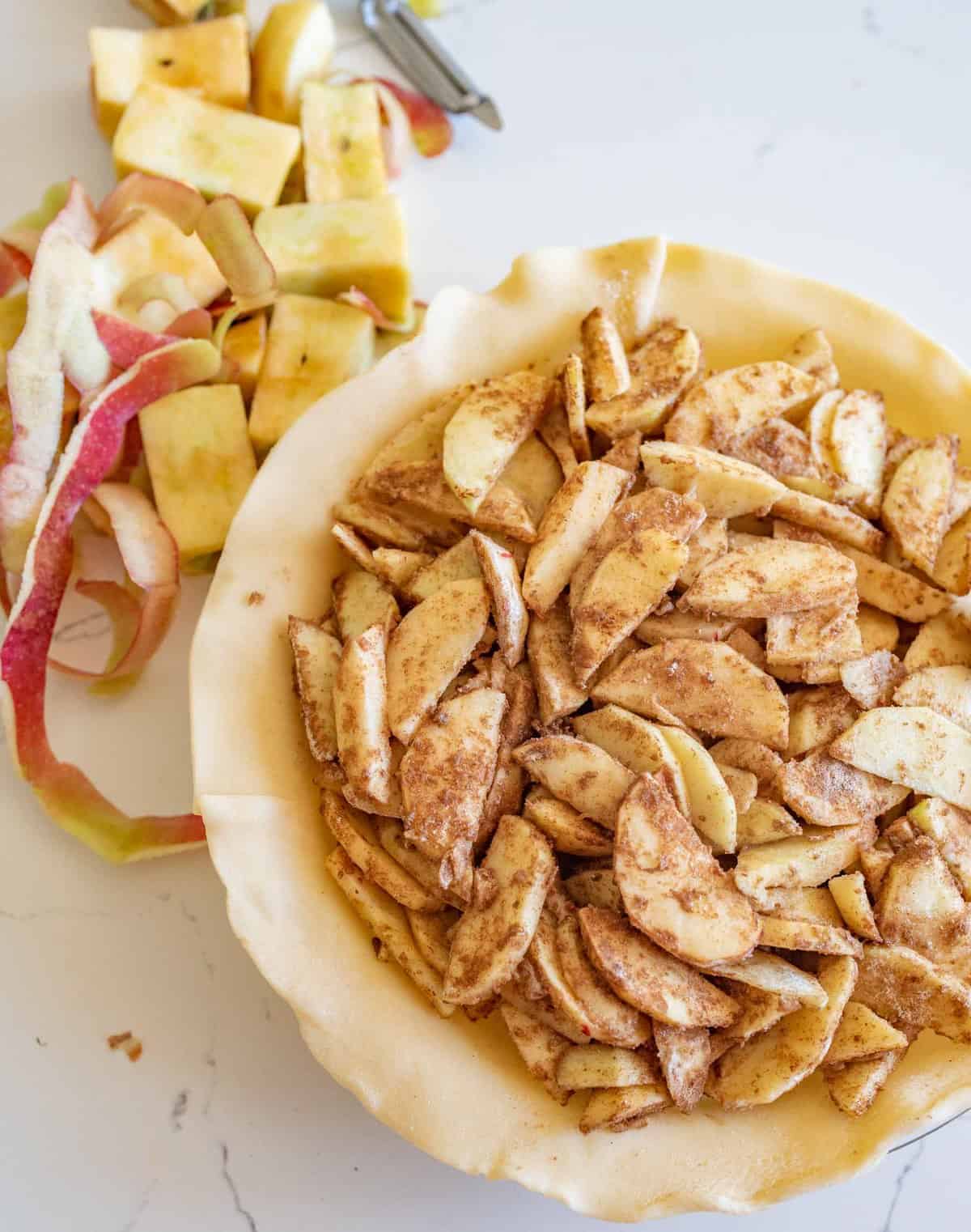 fresh apples in pie crust in clear pie dish.