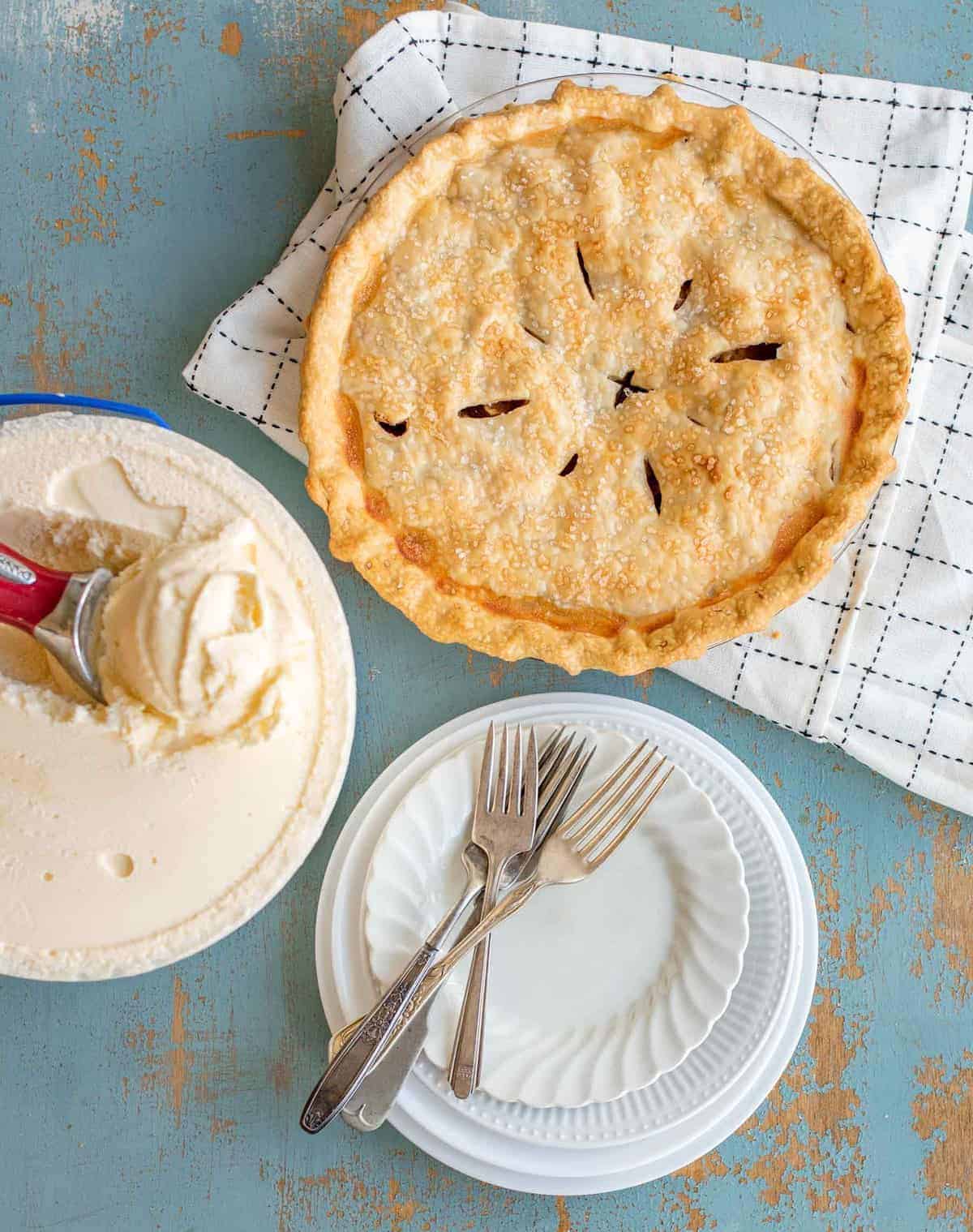 apple pie with ice cream and white plate with fork and spoon.